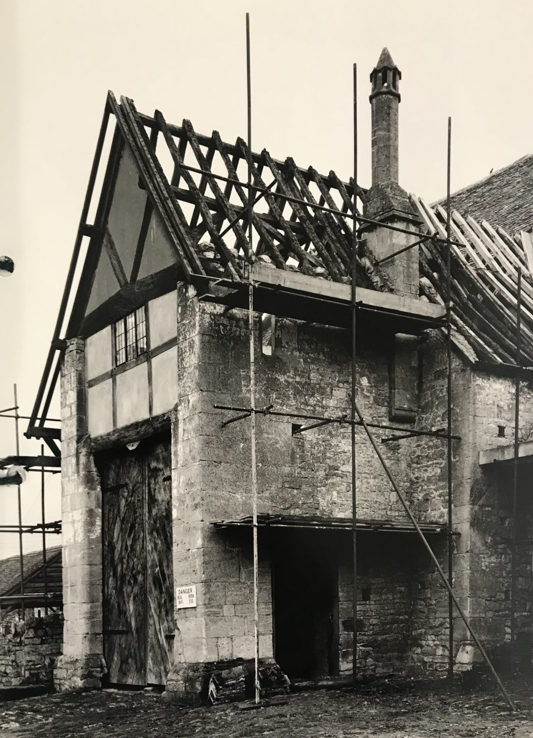 Scaffolding on one of Bredon's Barn's two large porches. Note the bailiff's solar room over the porch and fine medieval stone chimney with conical roof