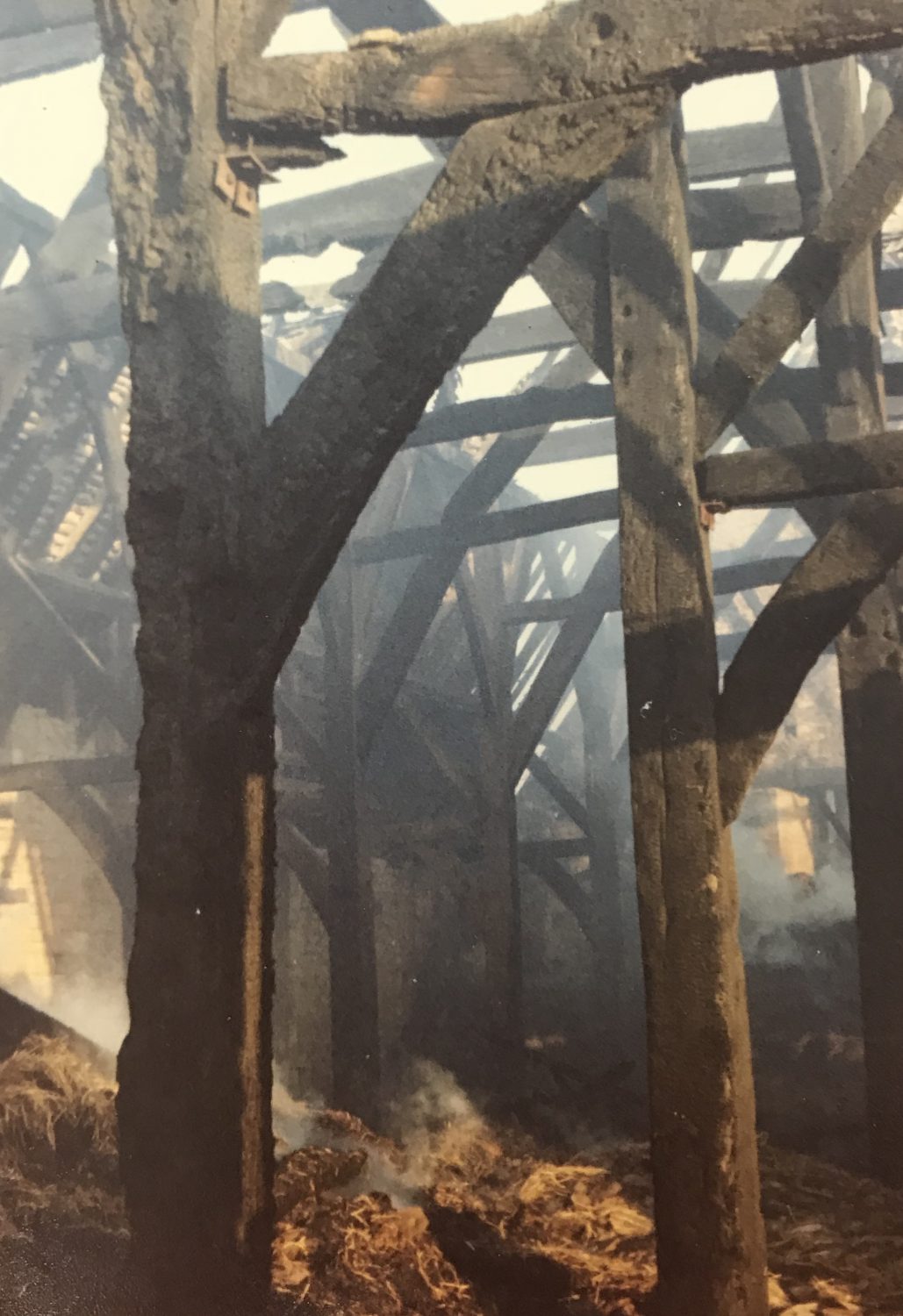 Smouldering hay and blackened timbers in the aftermath of the fire