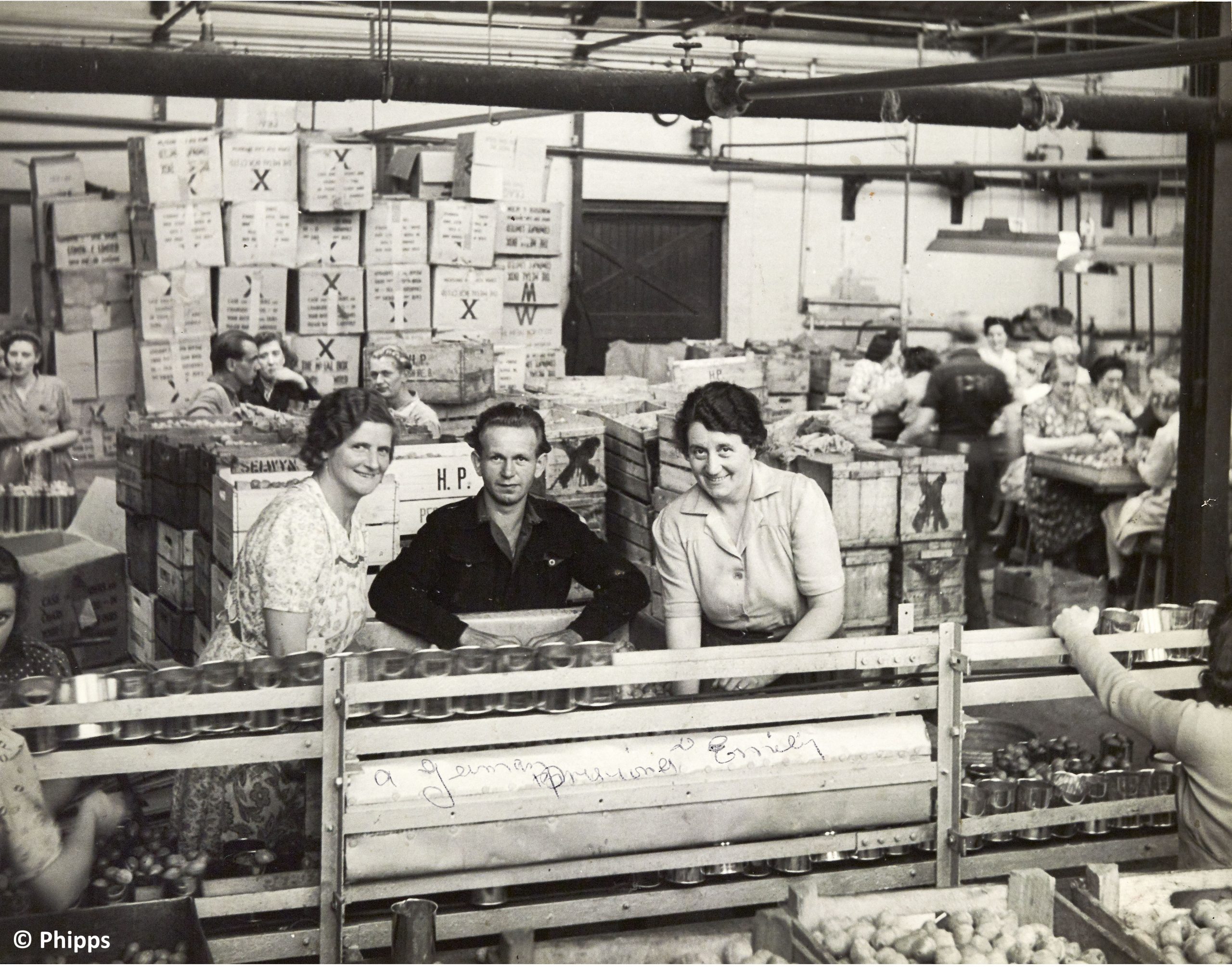 Workers at factory conveyor belt with boxes in background