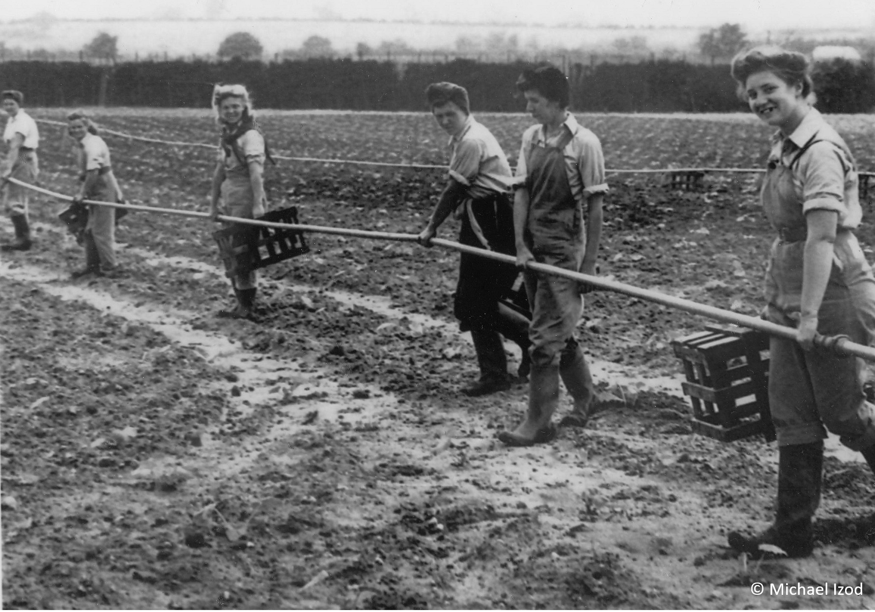 Land girls moving long metal water pipe