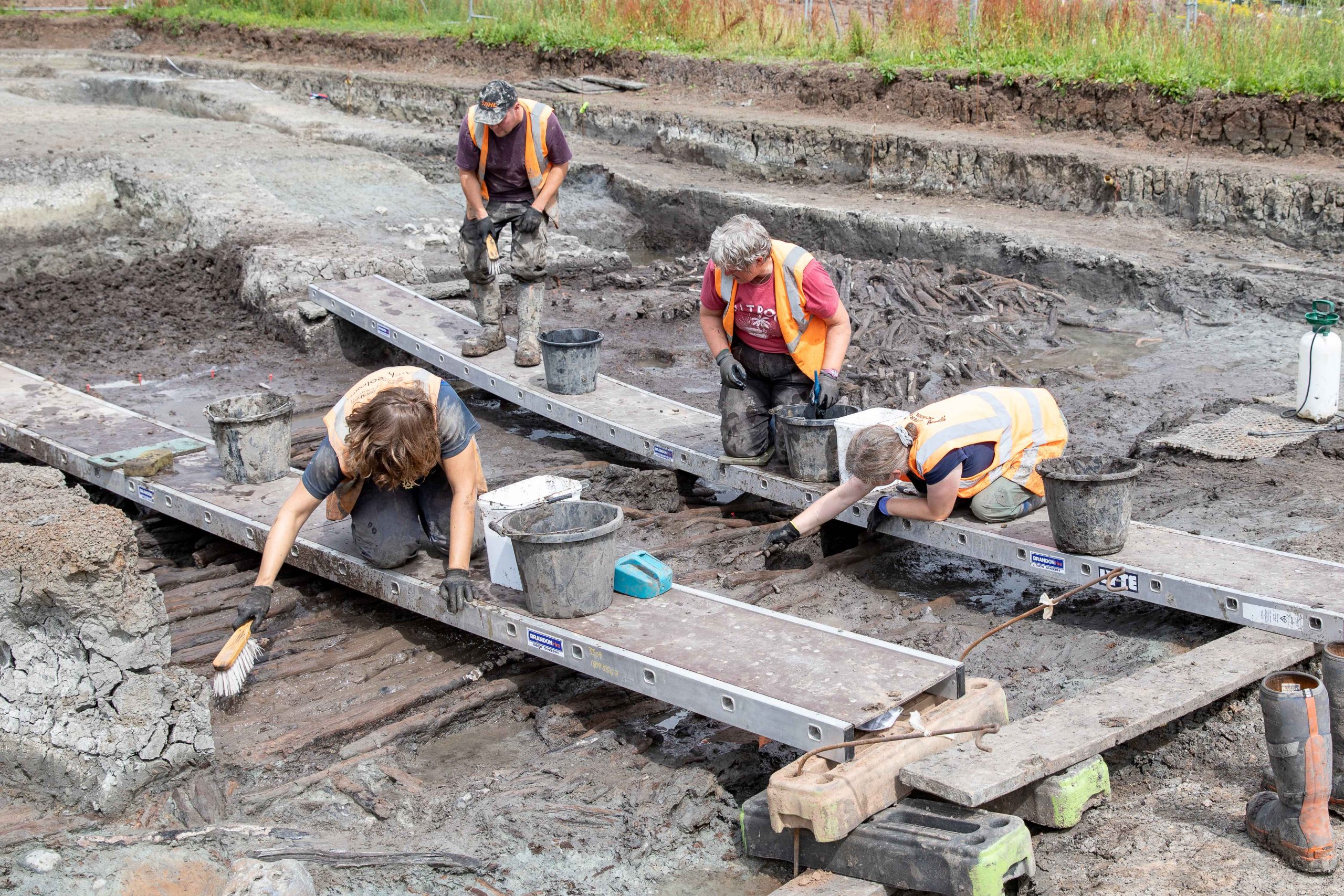 Excavation team on planks suspended above wooden trackway