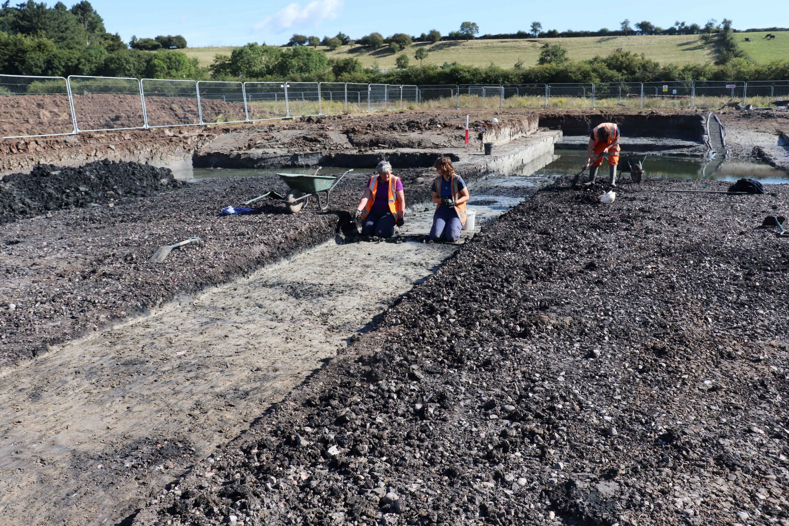 Two archaeologists working on section through large burnt mound