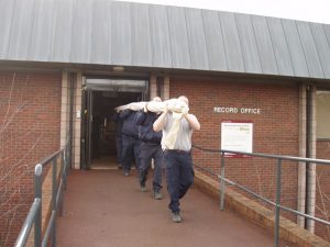 Picture of people carrying a large roll out of a building