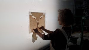 Rhonda using a wall light box to adjust a document