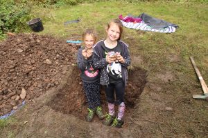 Children in a test pit holding some finds