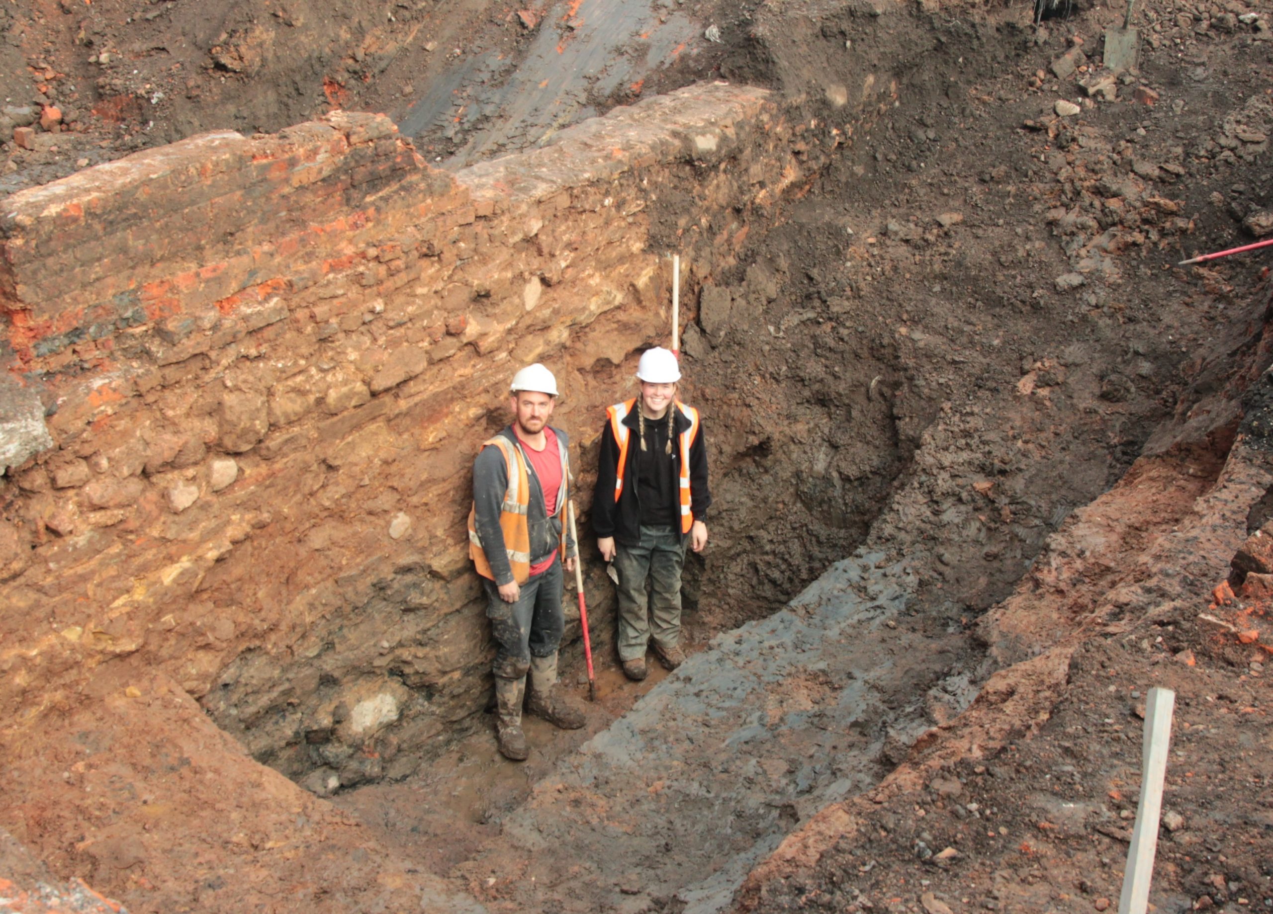 Two archaeologists in excavated moat slot