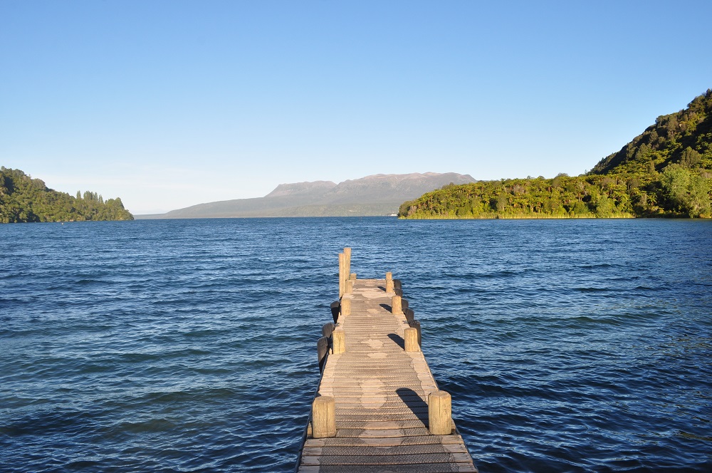 Wooden jetty into lake with tree covered hills beyond