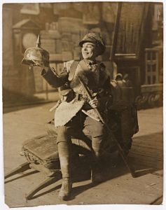 sepia photograph of Vesta Tilley in WWI soldiers uniform holding a German helmet