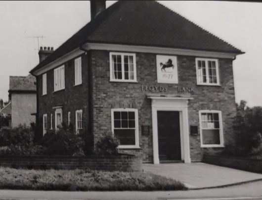 Black and white photo of a square, two storey building with large sash windows and Lloyds logo above the door.