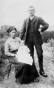 A black and white photograph of a man, woman and baby.