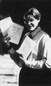 A black and white photograph of Sarah holding copies of a magazine that she created.