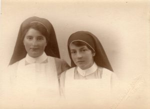 A black and white photograph of two young nurses in uniform dated c. 1922.