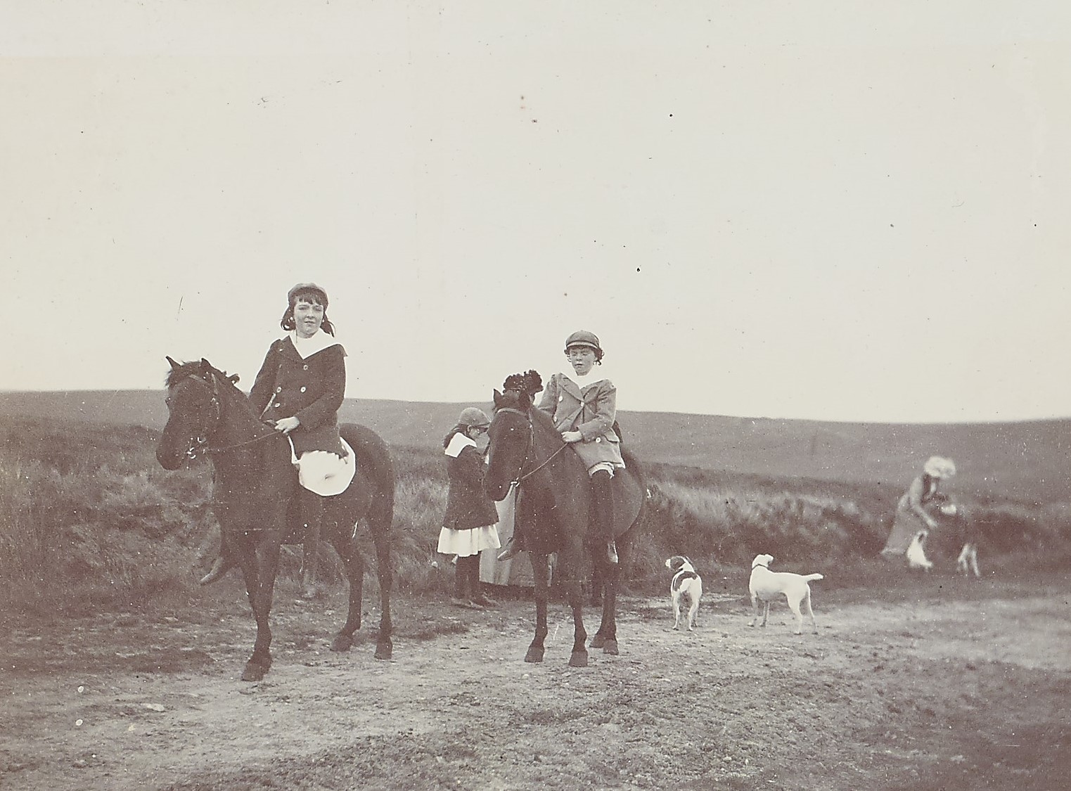 Black and white photograph of two children on horses outside on top of a hill