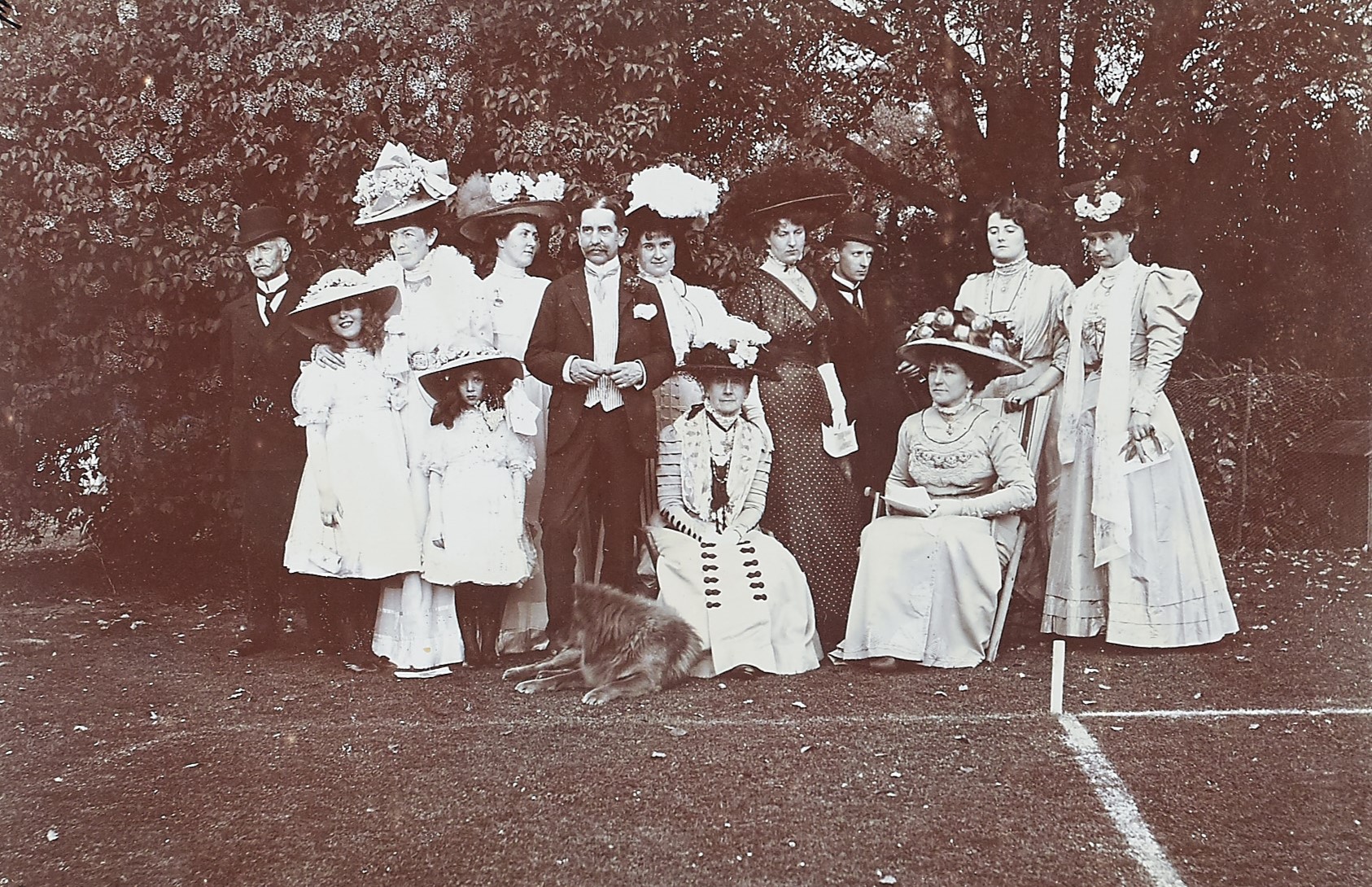 Black a white photograph of a group of people wearing suits and dresses