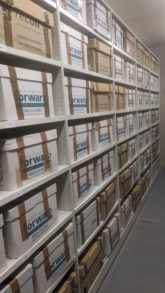 Coloured photograph of many boxes of Powick Hospital files in one of the strongrooms at Worcestershire Archive and Archaeology Service at The Hive, Worcester