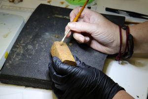 The box being cleaned by the conservator with a paint brush. 